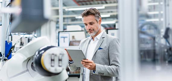 businessman with tablet at assembly robot in a factory